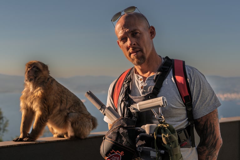 a man with a camera and a monkey sitting on a ledge