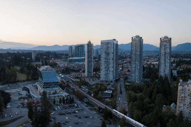 A train traveling through Surrey, BC with tall buildings