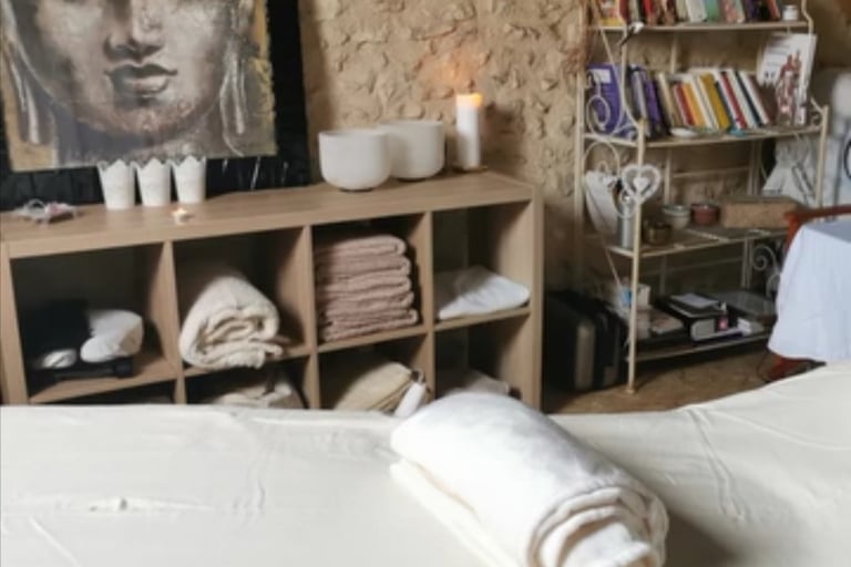 une table de massage, des bougies, tête de bouddha, bols de cristal, serviettes et draps