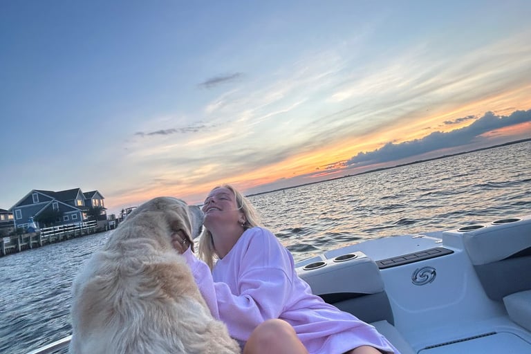Whitney sitting on a boat with her dog, enjoying a peaceful moment on the water.