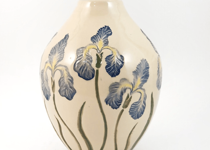 Elegant cream ceramic vase featuring hand-painted blue iris flowers on a white background.