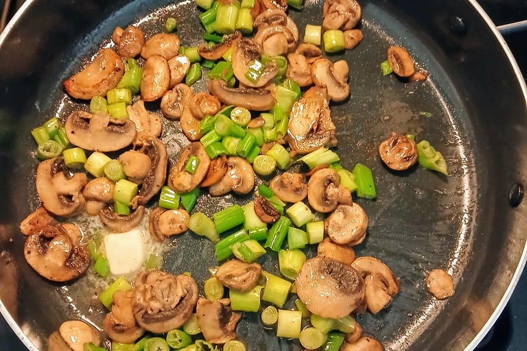 mushrooms and green onions cooking in a pan