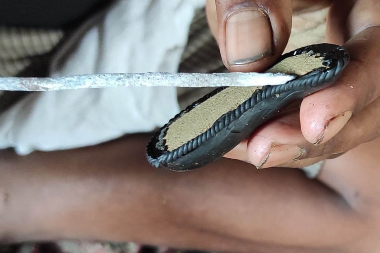 A Bastar artist carefully threading wax wires into a clay mould to craft intricate brass artwork using the lost-wax technique
