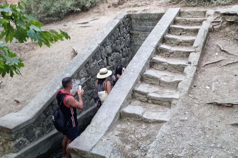 Tourists walking through the narrow stone entrance of the Panagia tou Sinti monastery ruins in Cyprus.