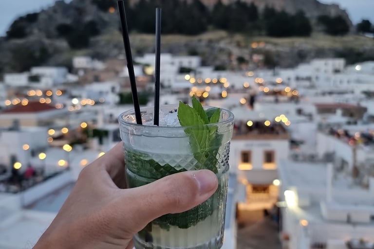 A refreshing mojito cocktail held at a rooftop bar overlooking the Acropolis of Lindos in Rhodes, Greece.