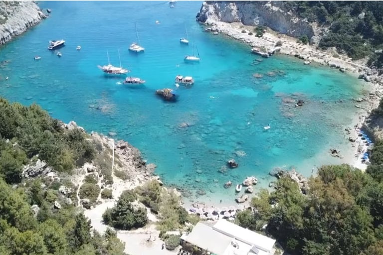 Aerial view of Anthony Quinn Bay in Rhodes, Greece, with boats anchored in clear turquoise Mediterranean waters.