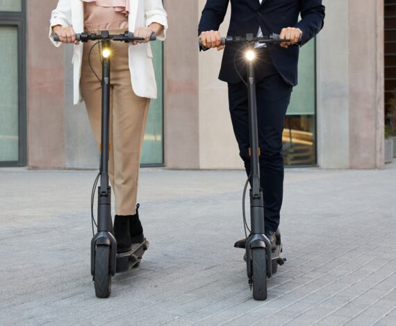a man and woman riding scooters on a city street