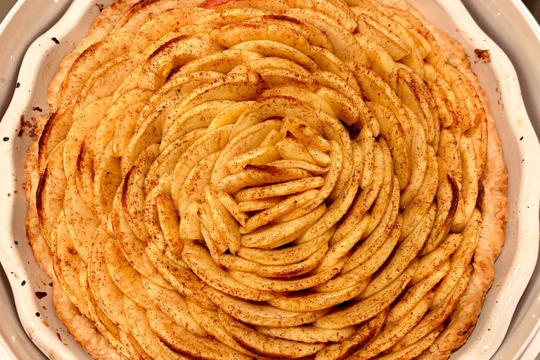 Freshly baked apple tart with thin slices arranged in a rose pattern and sprinkled with cinnamon.