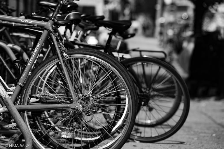 black and white shot of bicycle spokes and wheels parked on a brooklyn sidewalk