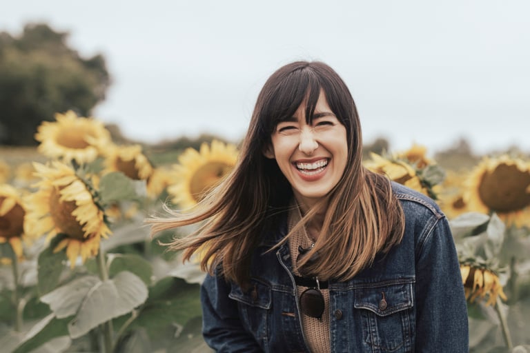 brunette woman smiling in field of sunflowers