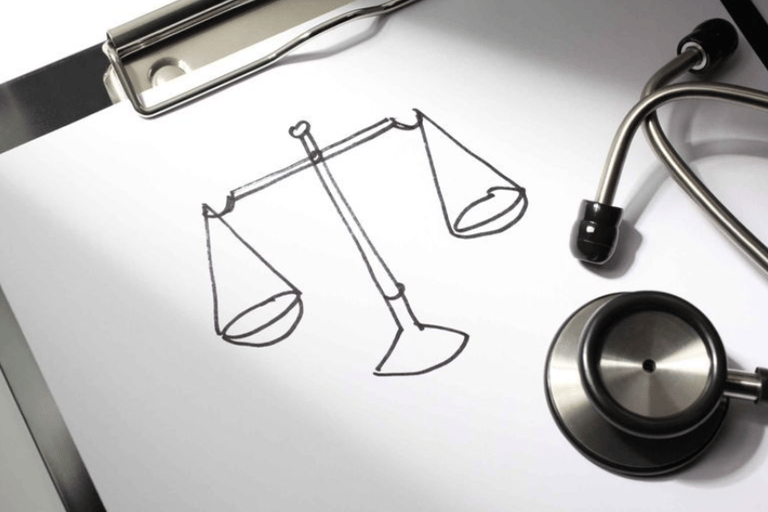 um estetoscópio sobre folha de papel com desenho de balança da justiça