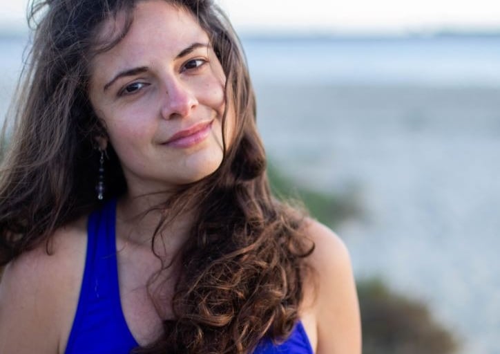 a woman in a blue tank top and earrings