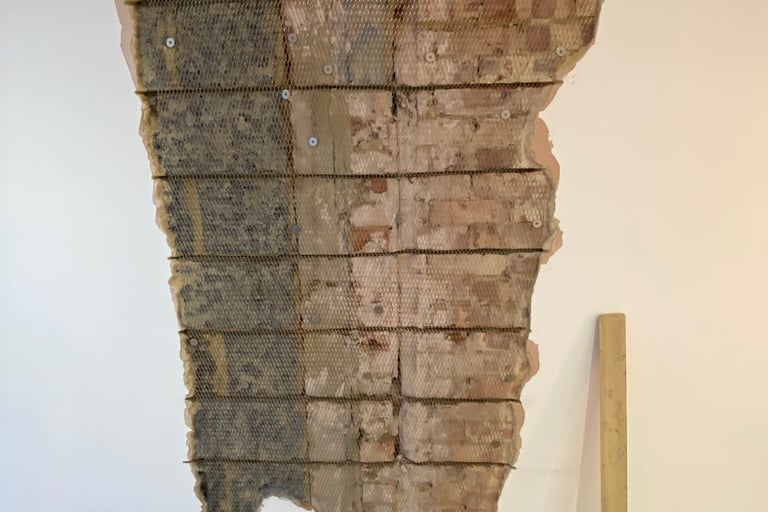 An exposed brick wall showing structural reinforcement with steel mesh and wall ties during home renovation.