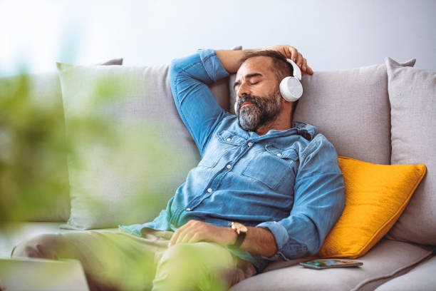 Homme écoutant chez lui une relaxation sonore enregistrée spécialement pour lui.