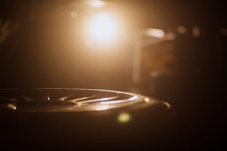 Cinematic close-up of a steel tongue drum with warm stage lighting and soft bokeh background.