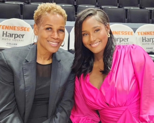 Two women sit together, enjoying a basketball game, surrounded by fans and the vibrant atmosphere.