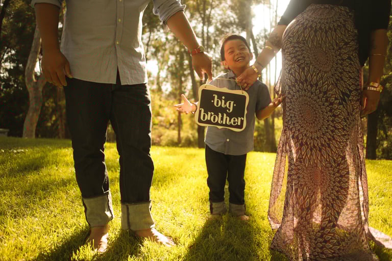 a family photo holding a sign that says big brother and the toddler big brother