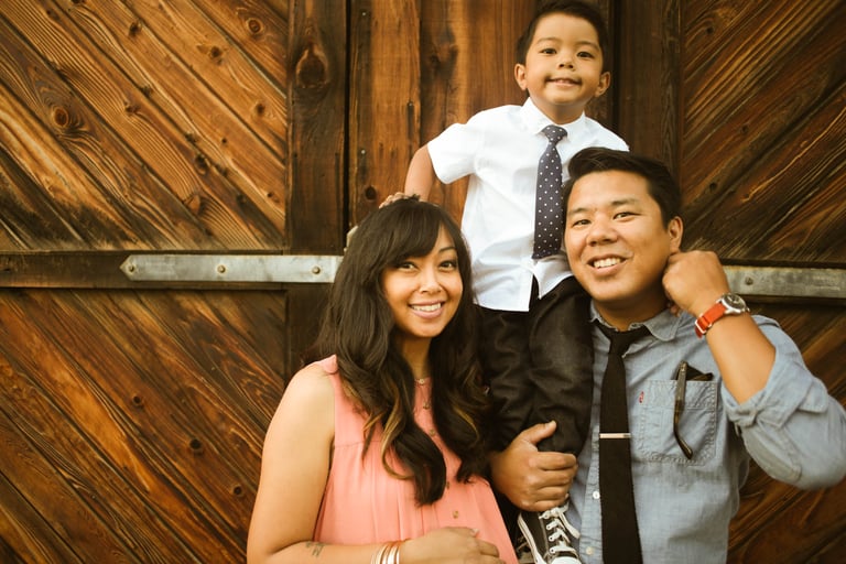 parents and son standing in front of wooden barn door photo