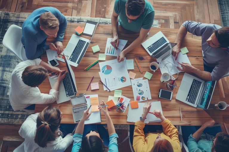 Aerial view of a creative team collaborating on a marketing project with laptops and data charts.