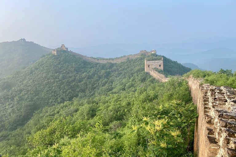 a man standing on a mountain top with a view of the great wall of china