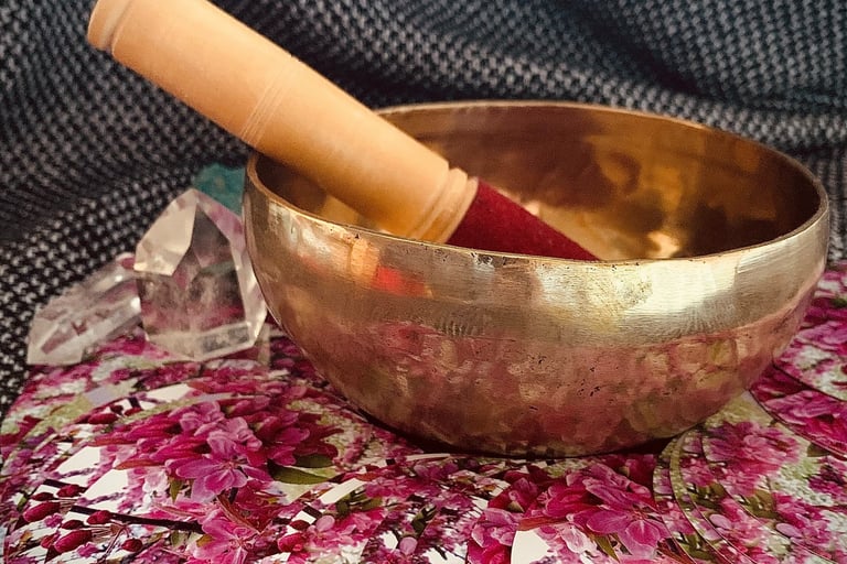 A singing bowl next to crystals and an oracle deck