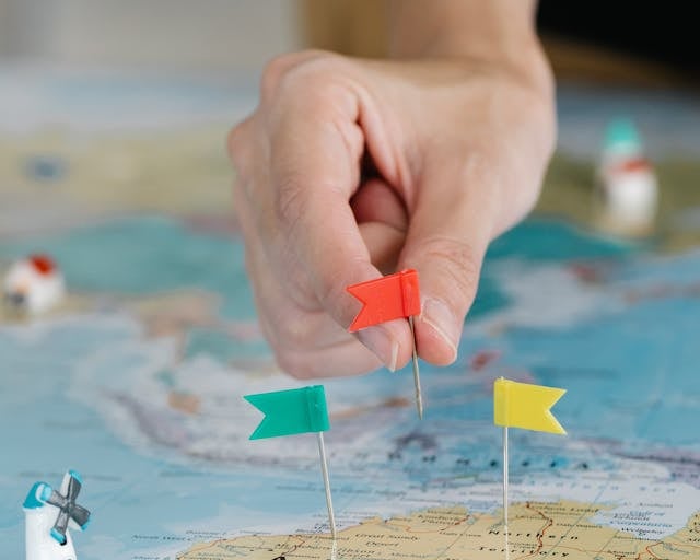 a person holding a pin pinpoint flag on a map of the world