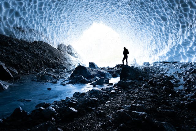 a person standing in a cave with a view of a glacier
