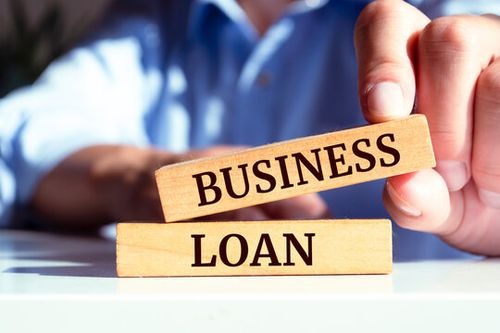 a man holding a wooden block with the words business loan dream inc