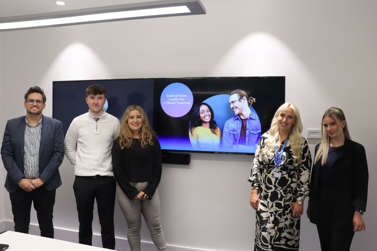 Three apprentices, a sales lead and Tim stand in front of a screen for UK&I apprenticship re-launch.