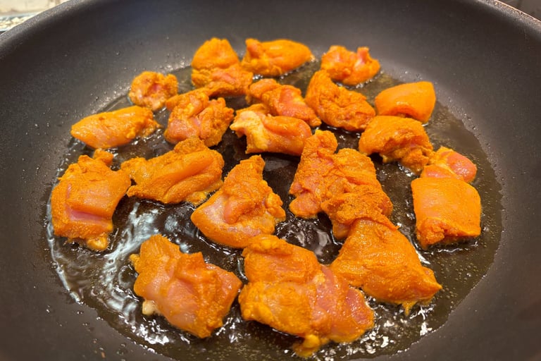 chopped marinated chicken thighs frying in pan