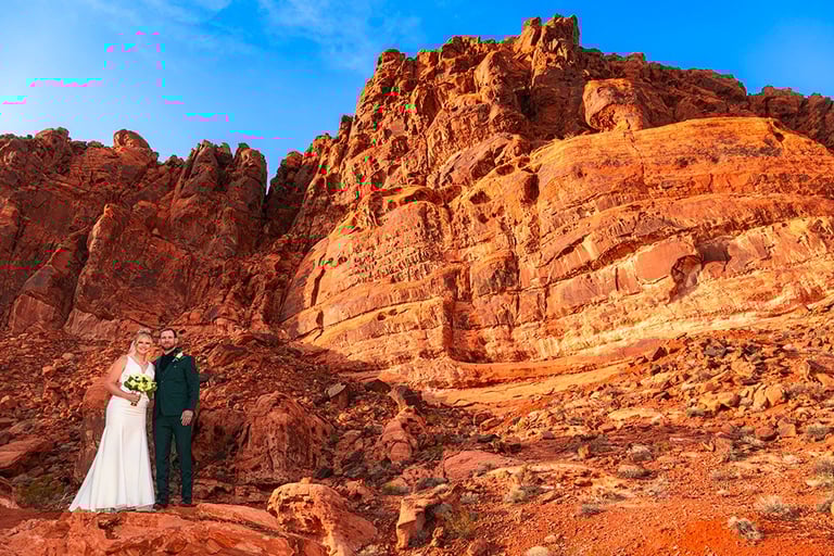 a bride and groom standing on a rocky mountain