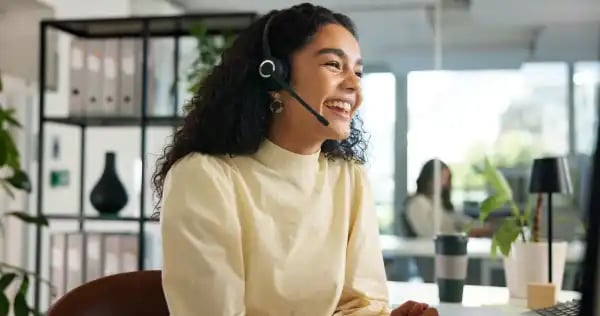Smiling customer service representative wearing a headset in a modern office workspace