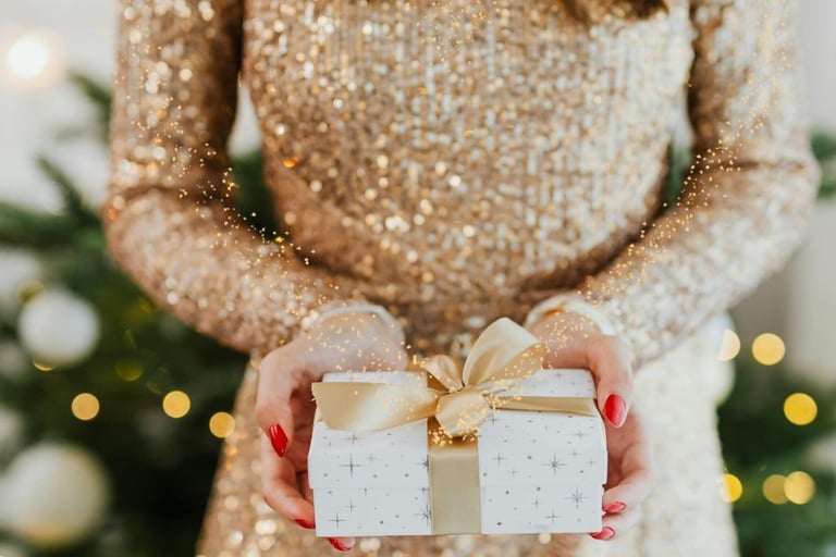 a woman holding a present box with a gold bow