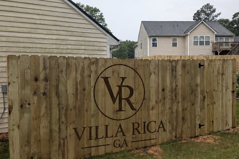 Custom wood privacy fence in Villa Rica GA featuring a laser engraved logo and residential neighborhood view.