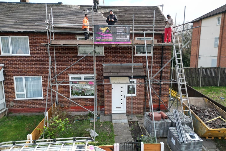 Professional roofers from F&N Roofing performing repairs on a residential brick house using scaffolding.