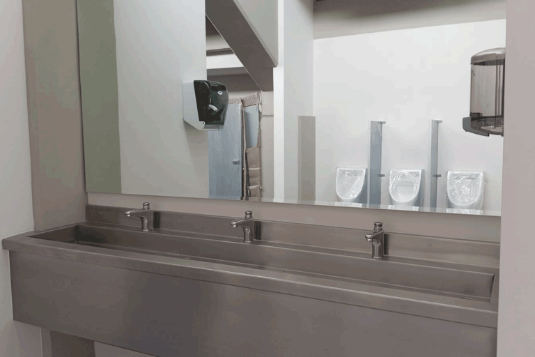 Lavamanos de acero inoxidable con espejo grande en sanitarios públicos | KARÄNA