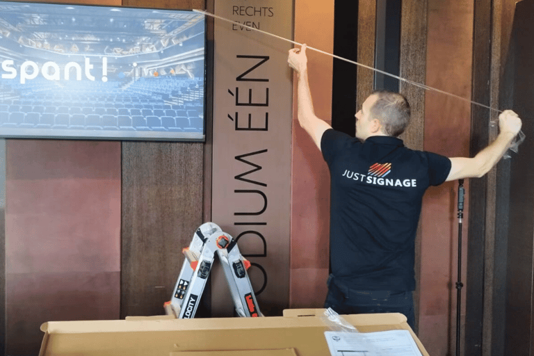 JustSignage, a man is hanging a display