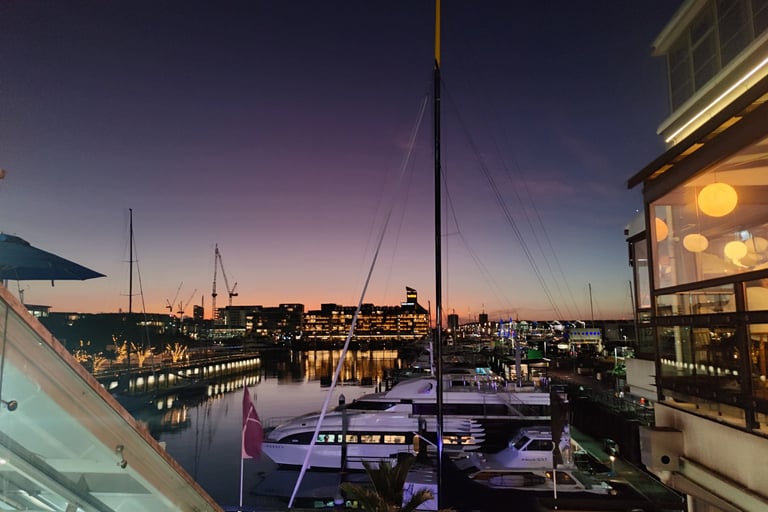 Viaduct Marina, Auckland, New Zealand. View of sunset, city lights and moored yachts
