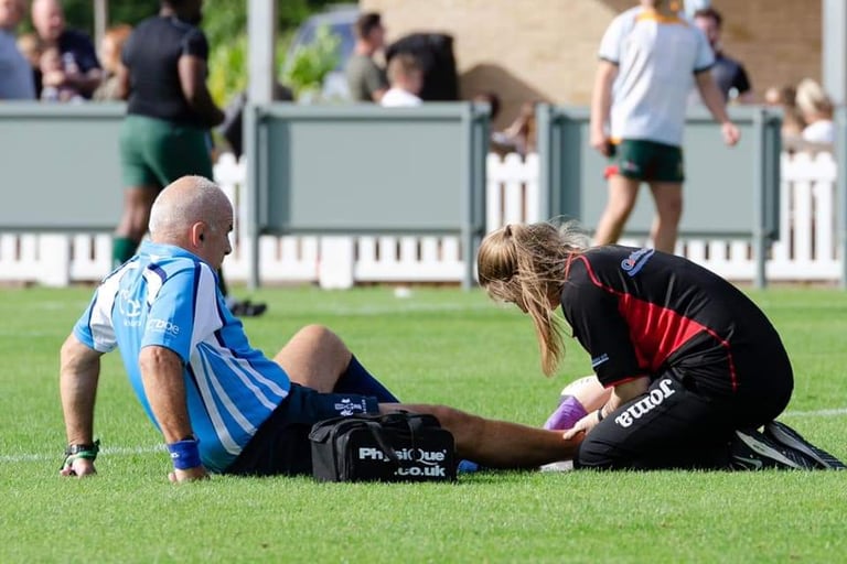 A referee receiving on-pitch assistance for an ankle injury.