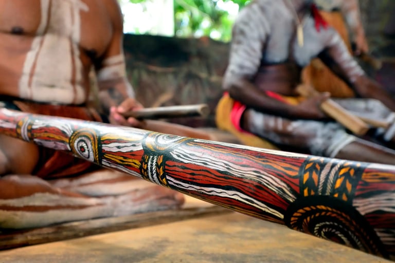 two Aboriginal men 1 playing a didgeridoo 1 playing clapsticks