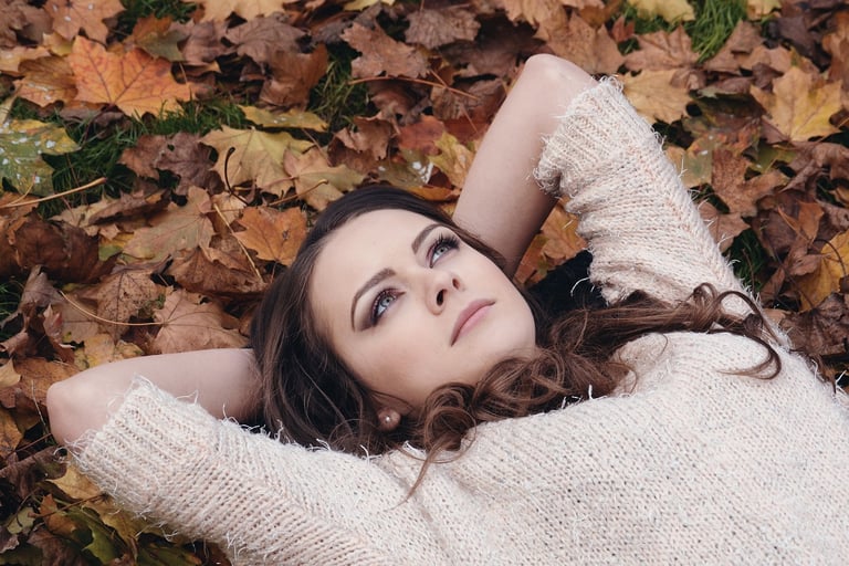 a woman laying on the ground in front of a pile of leaves
