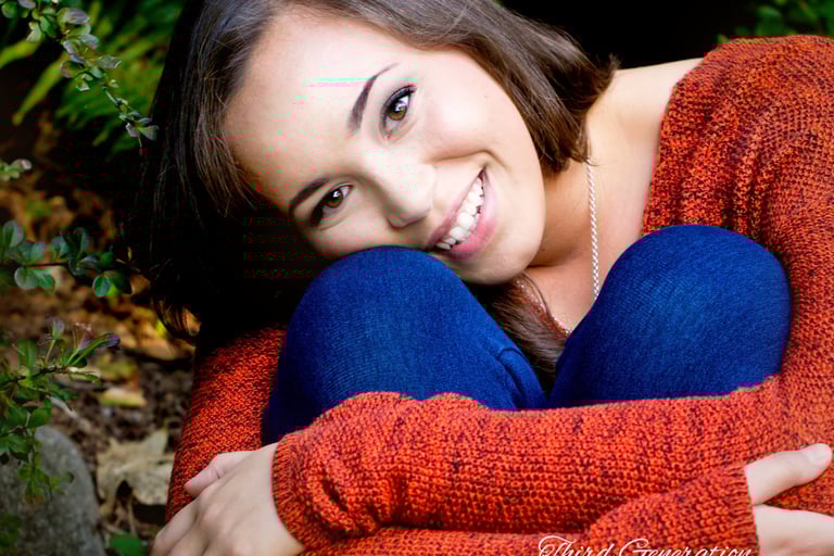 a woman in a red sweater and jeans sitting on a bench