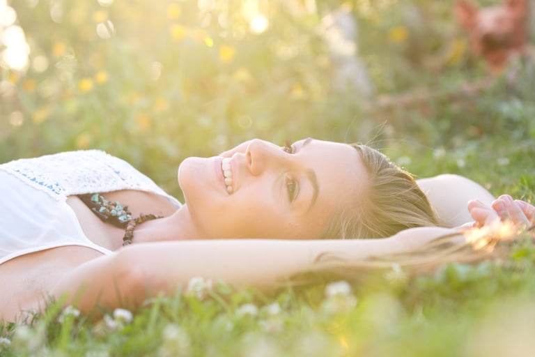 a woman laying on the grass in the sun