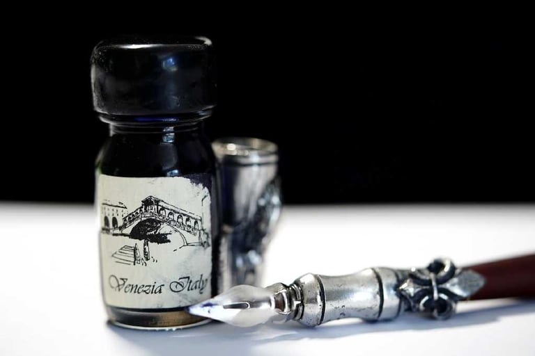 a bottle of ink ink and a pen on a table