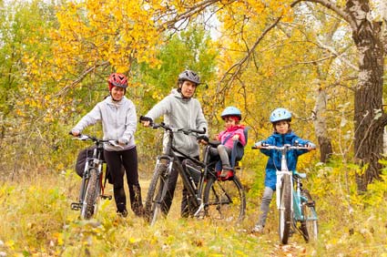 family riding bikes in the fall leaves