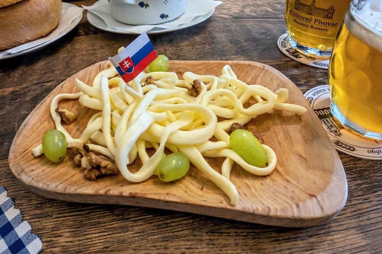 Aperitivo típico eslovaco servido en una tabla de madera sobre una mesa rústica, con una cerveza