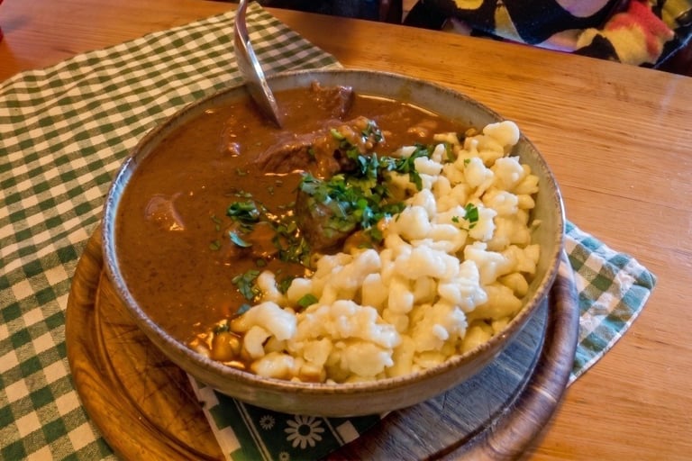 Cuenco de gulasch vienés (estofado de carne) con salsa oscura, servido con pasta spätzle y perejil