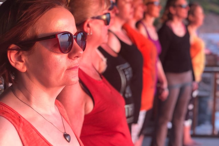 A group of women stand looking out to sea with a calm presence