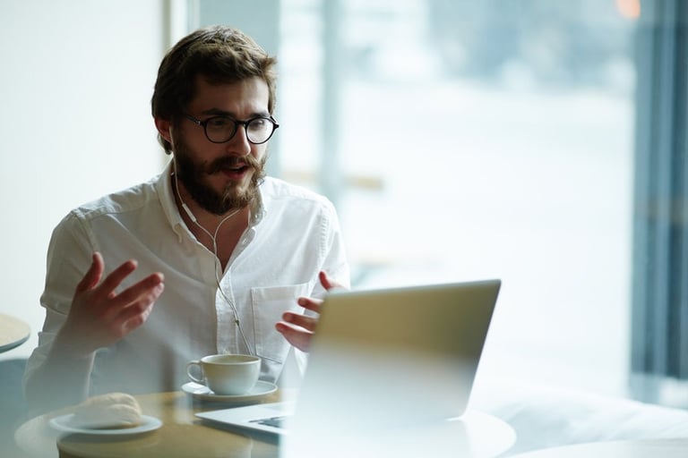 a man sitting at a table with a laptop and a cup of coffee