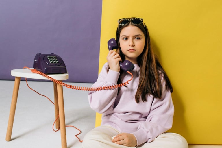 Photo d'une adolescente assise qui tient le combiné d'un téléphone du XXe siècle